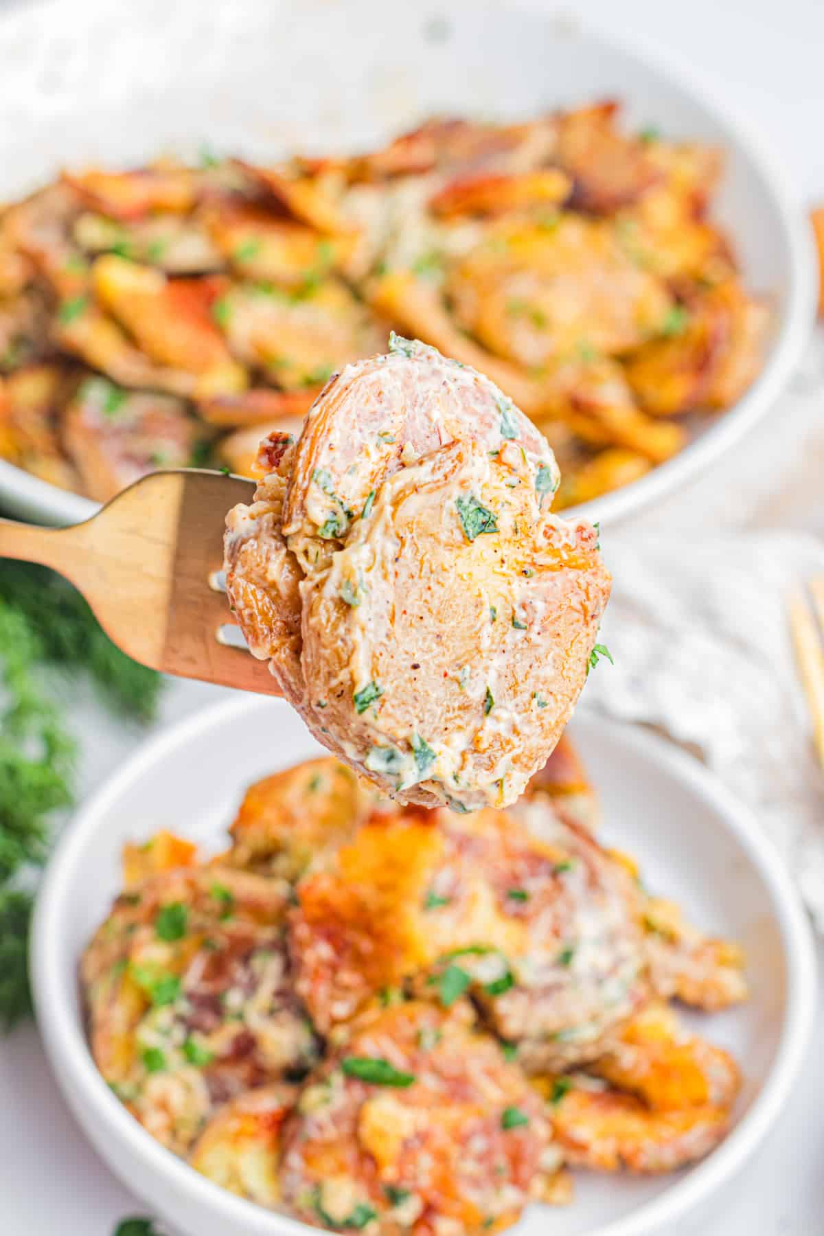 Fork holding Crispy Smashed Potato Salad with creamy lemon herb dressing, roasted baby potatoes, fresh herbs, and crispy potato edges
