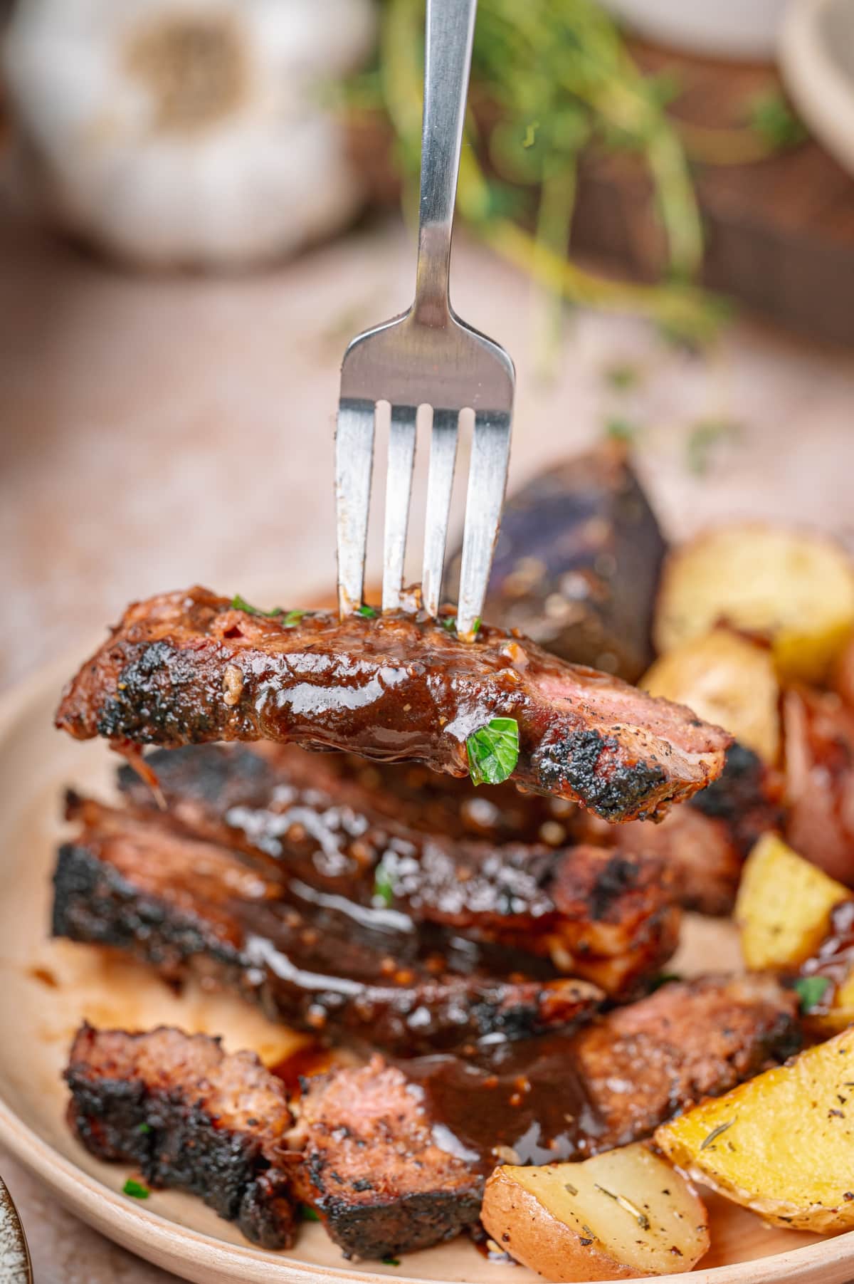 Fork lifting sliced steak coated in dark stout pan sauce. Dark stout pan sauce spooned over sliced steak with a charred cocoa spice crust.