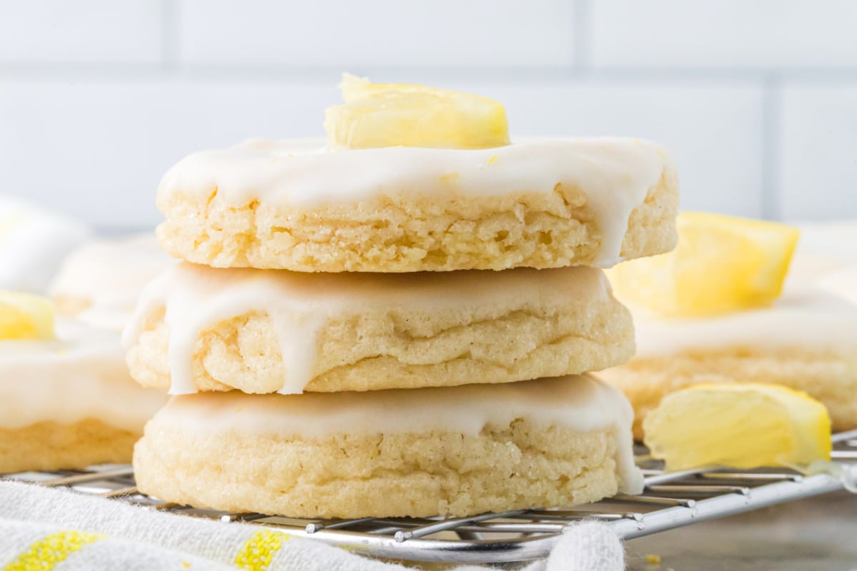 Glazed lemon sugar cookies stacked on a cooling rack showing their soft centers and thick lemon glaze