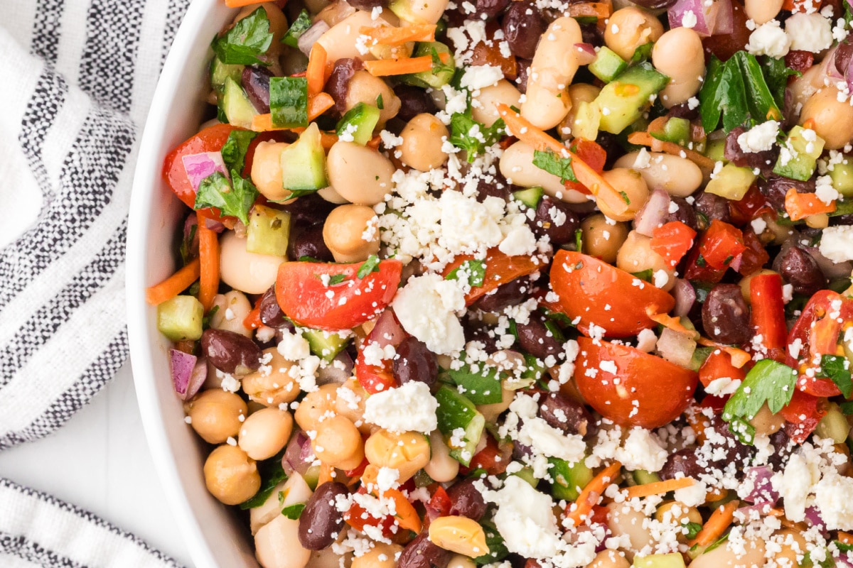 High protein dense bean salad with chickpeas, black beans, cannellini beans, feta cheese, tomatoes, cucumber, and parsley