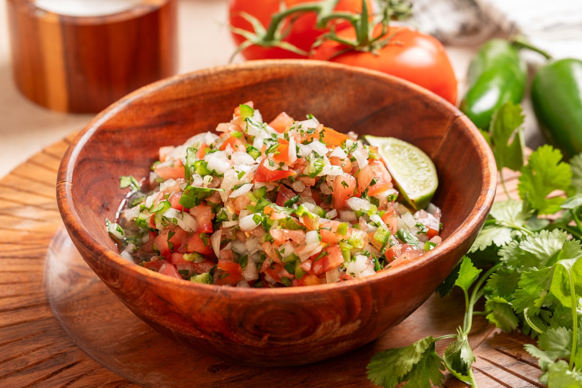Homemade pico de gallo in a wooden bowl with seeded tomatoes, cilantro, jalapeño, onion, and fresh lime