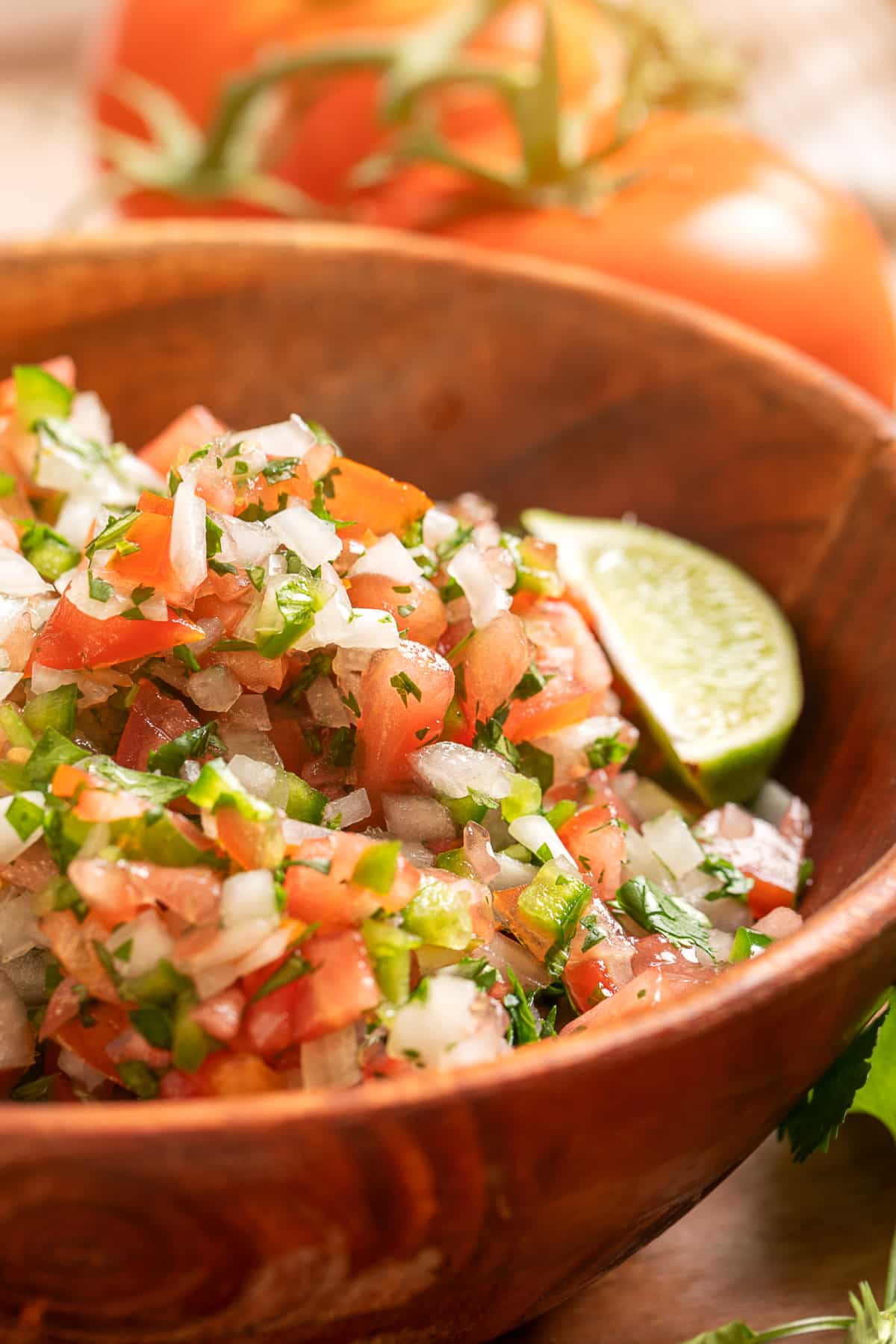 Homemade pico de gallo with seeded tomatoes, white onion, jalapeño, cilantro, and lime in a wooden bowl