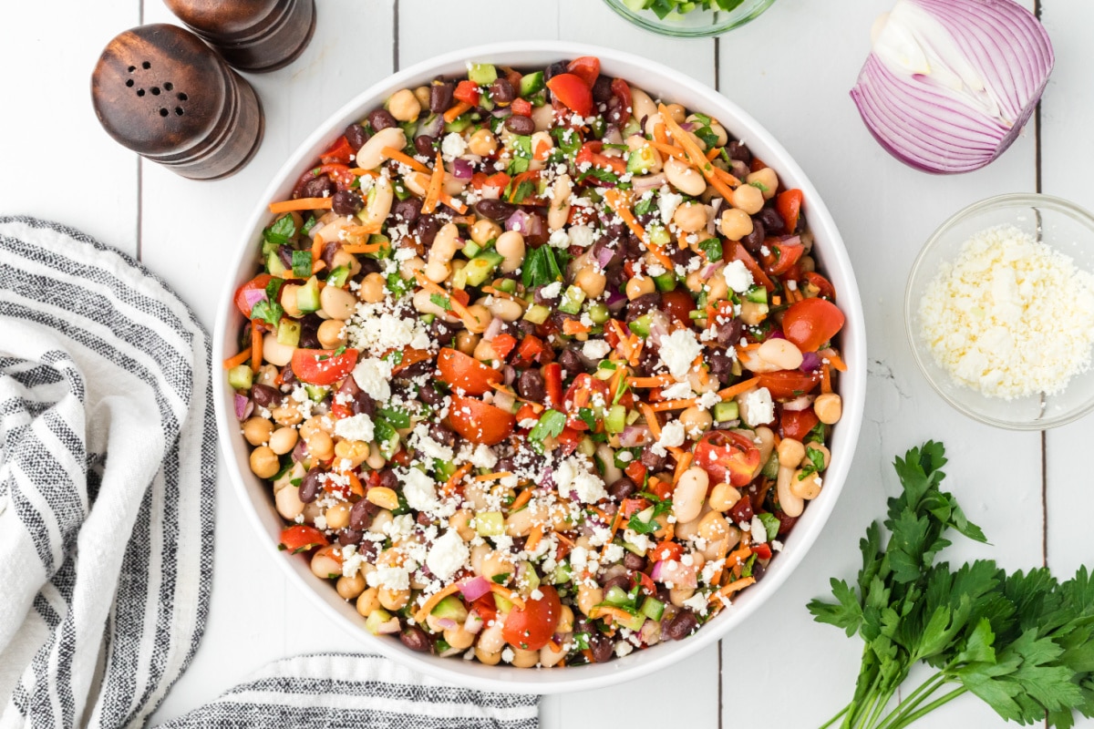 Lemon Dijon dense bean salad with black beans, chickpeas, cannellini beans, feta cheese, tomatoes, carrots, and cucumber