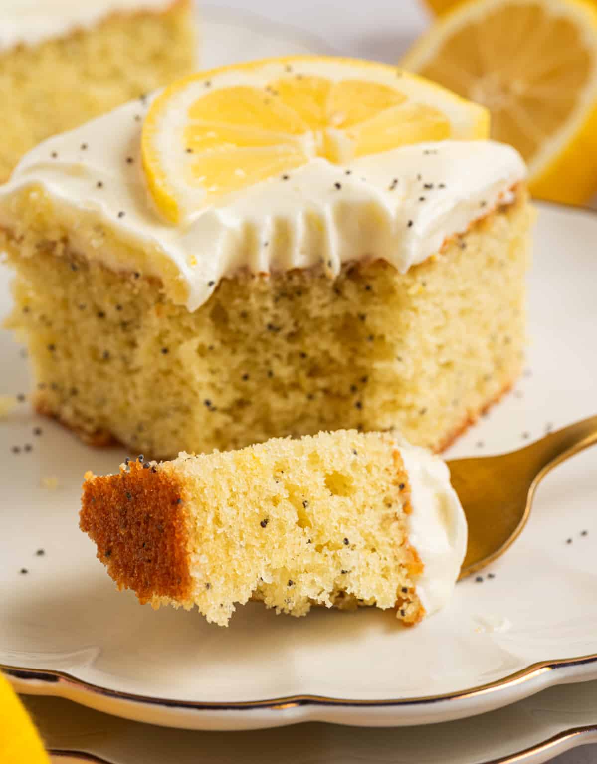 Lemon poppy seed cake bite on a fork with cream cheese frosting Close-up of lemon poppy seed cake with cream cheese frosting and a fork holding a bite, showing soft crumb and golden edges