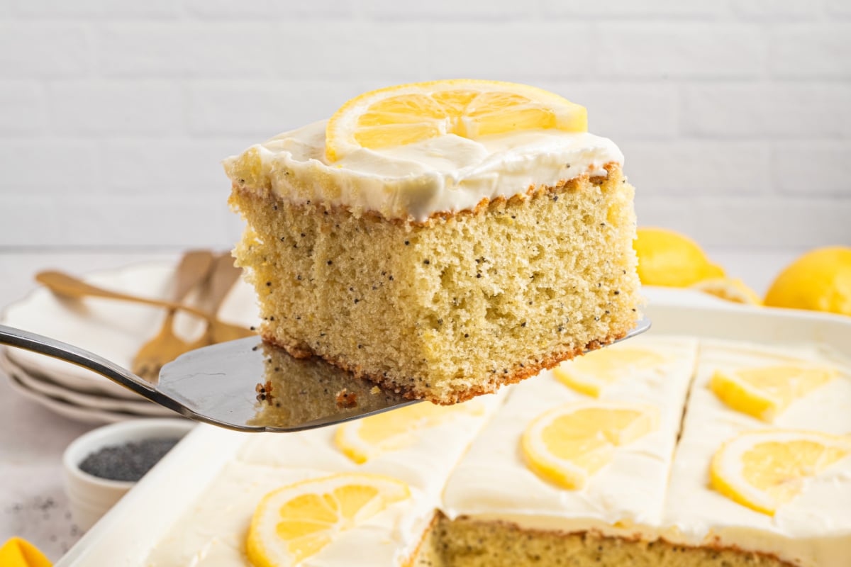 Lemon poppy seed cake slice lifted on a fork with cream cheese frosting Fork lifting a slice of lemon poppy seed cake with cream cheese frosting, showing soft crumb and poppy seeds