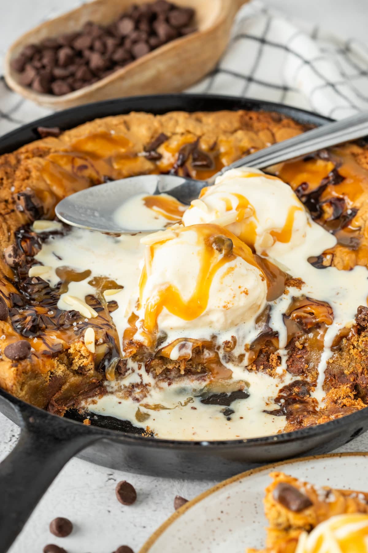 The caramel layered through the middle melts into the center and turns this skillet cookie into a full spoon dessert. Molten center of a salted caramel skillet cookie with melting vanilla ice cream, chocolate chunks, caramel sauce, and crisp golden cookie edges in a cast iron skillet.