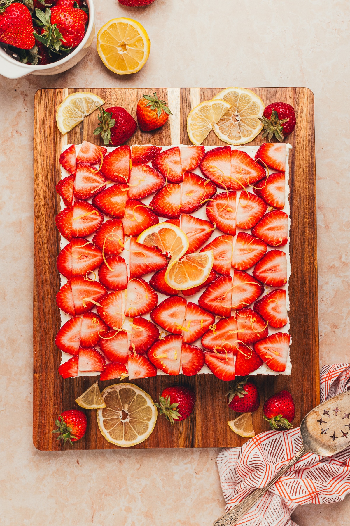 Overhead view of No-Bake Strawberry Lemon Icebox Cake with strawberries and lemon Overhead view of No-Bake Strawberry Lemon Icebox Cake topped with sliced strawberries, lemon zest, and mascarpone cream.