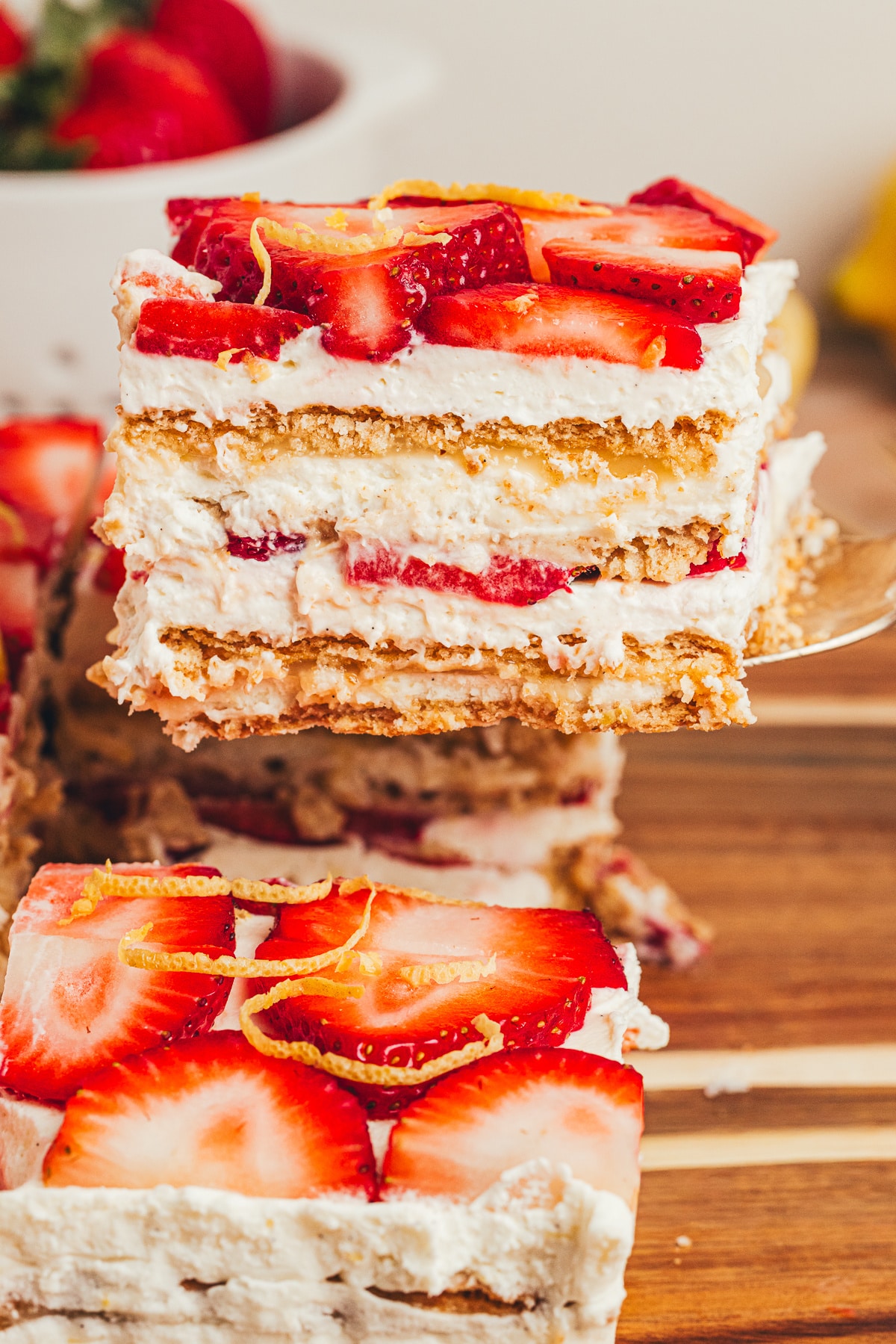 Lifted slice of No-Bake Strawberry Lemon Icebox Cake with lemon curd layers Lifted slice of No-Bake Strawberry Lemon Icebox Cake showing mascarpone cream, lemon curd, strawberries, and softened graham cracker layers.