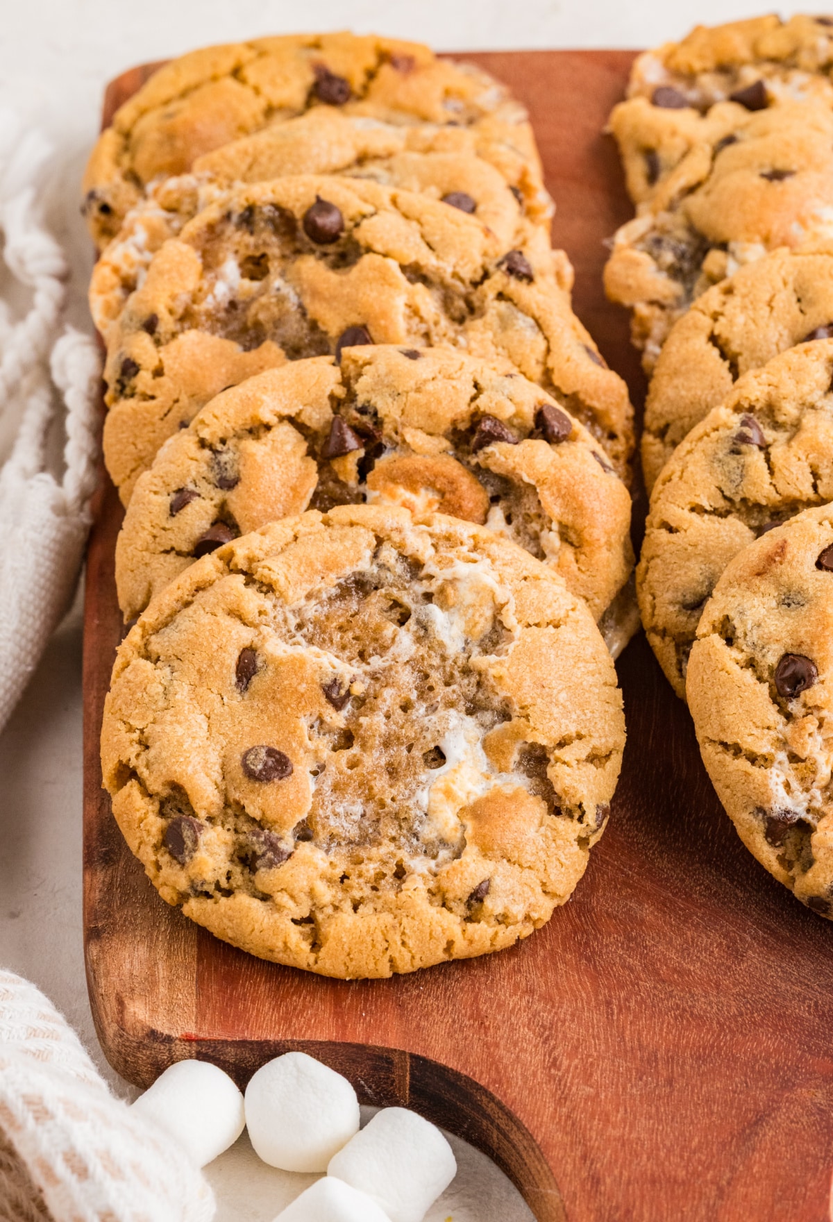 Peanut butter marshmallow cookies on a wooden serving board with toasted marshmallow pockets and mini chocolate chips.