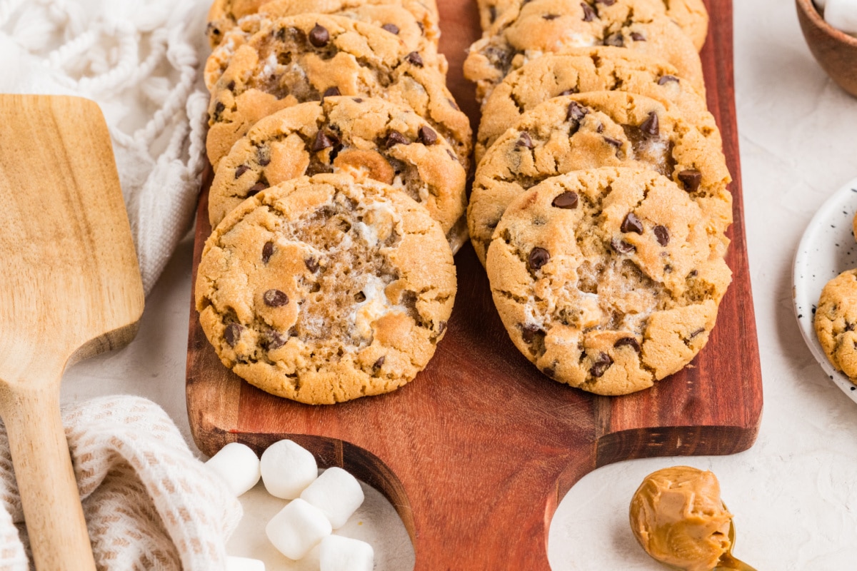 Peanut butter marshmallow cookies arranged on a wooden serving board with visible toasted marshmallow pockets and mini chocolate chips.