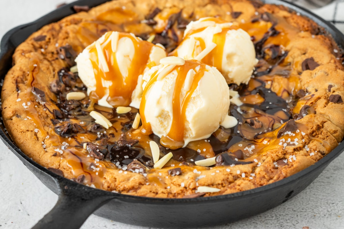 Crisp golden edges, molten caramel through the middle, and enough melting ice cream to turn this skillet cookie into full dessert. Salted caramel chocolate chip skillet cookie topped with vanilla ice cream, caramel sauce, melted chocolate, flaky sea salt, and chocolate chunks in a cast iron skillet.
