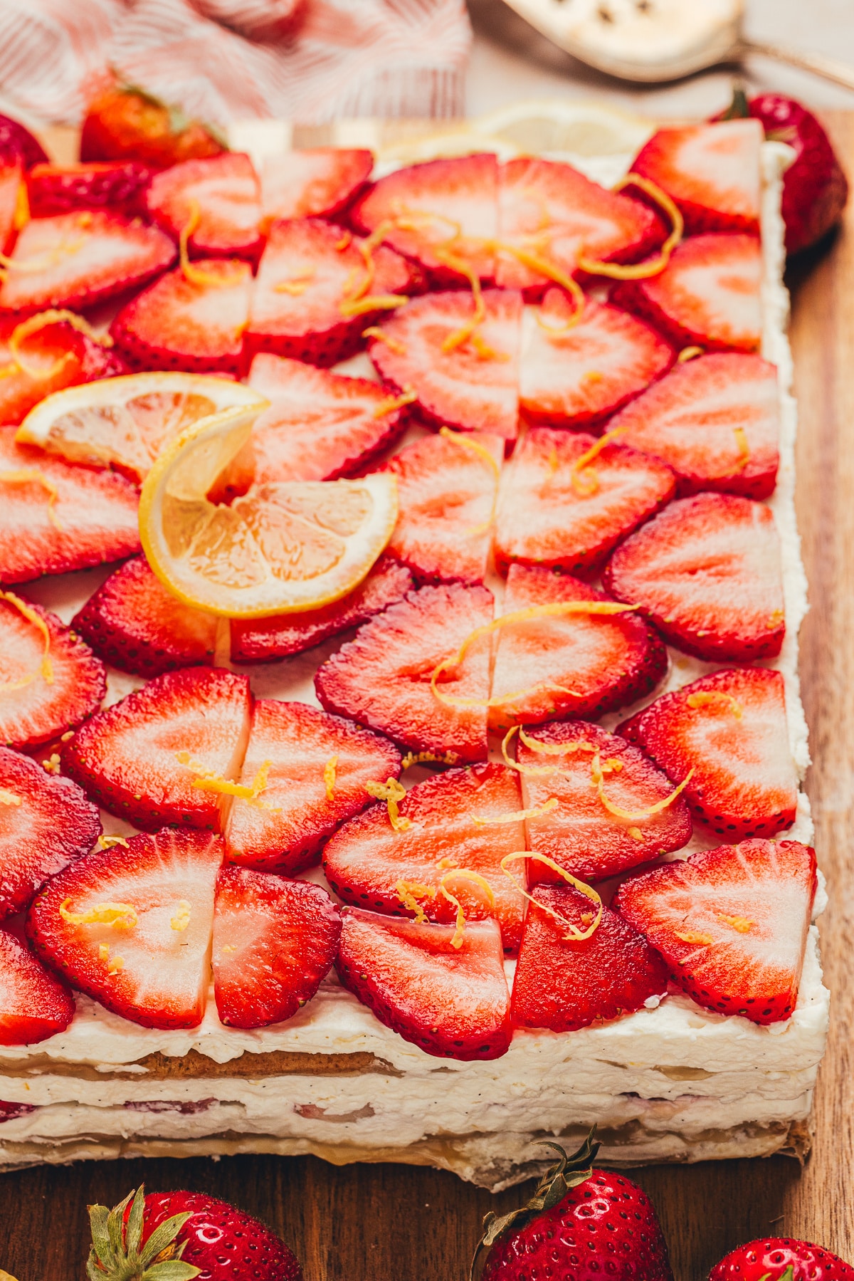 Close view of strawberry lemon icebox cake with strawberries and lemon zest Close view of strawberry lemon icebox cake topped with sliced strawberries, lemon zest, and mascarpone cream layers.
