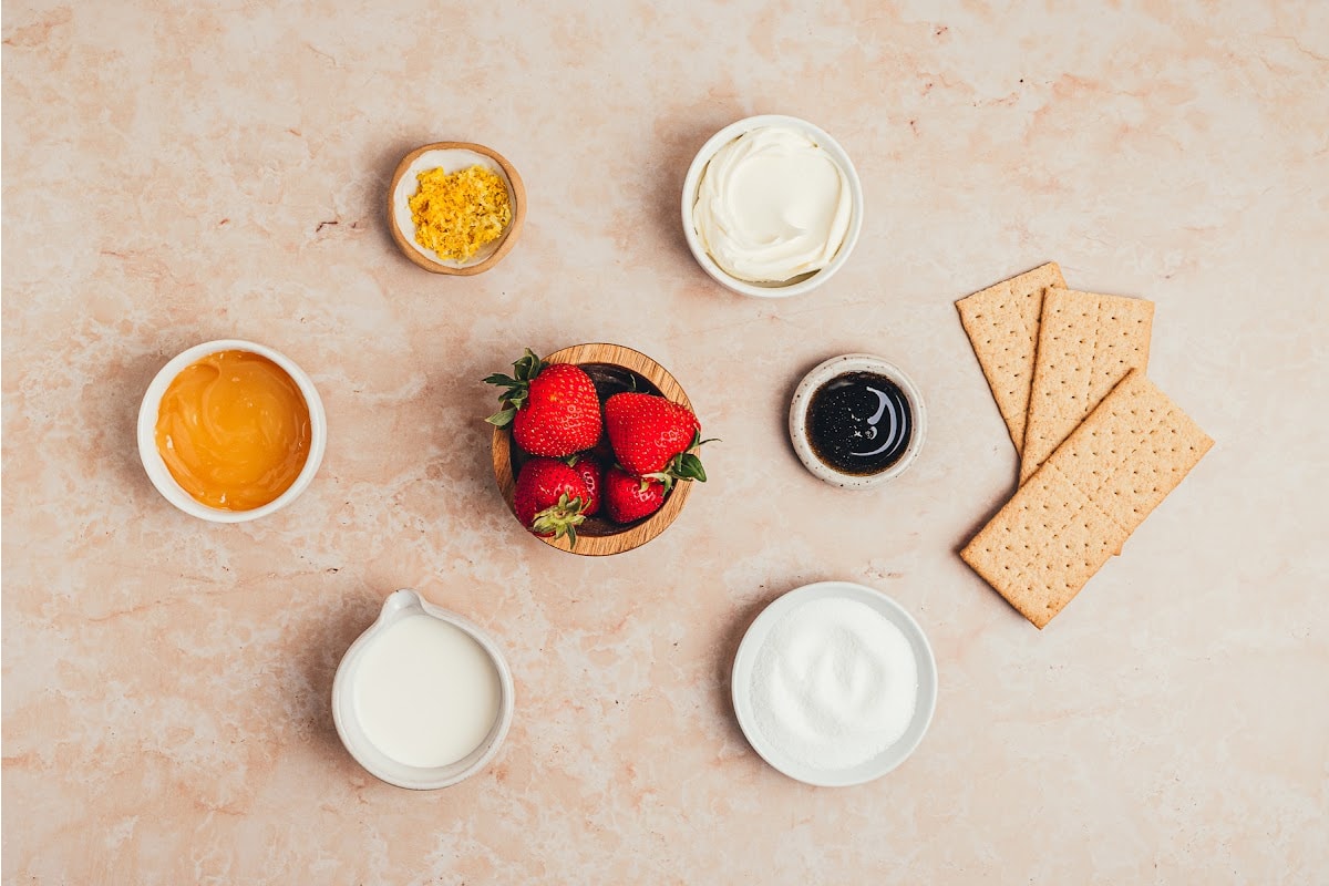 Ingredients for strawberry lemon icebox cake with mascarpone and lemon curd Ingredients for strawberry lemon icebox cake including mascarpone, lemon curd, strawberries, graham crackers, cream, vanilla, sugar, and lemon zest.