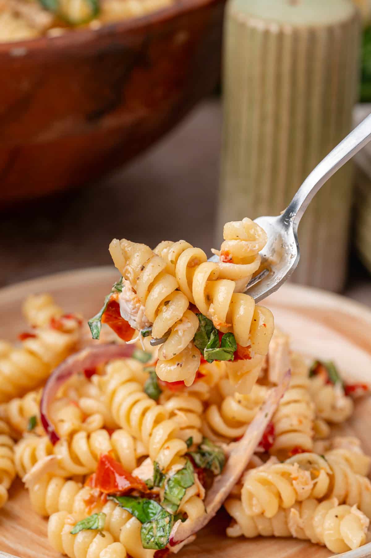 Forkful of cold chicken pasta salad with rotini, basil, Parmesan, and sun-dried tomato dressing Forkful of Sun-Dried Tomato Chicken Pasta Salad with rotini, basil, red onion, and chopped sun-dried tomatoes