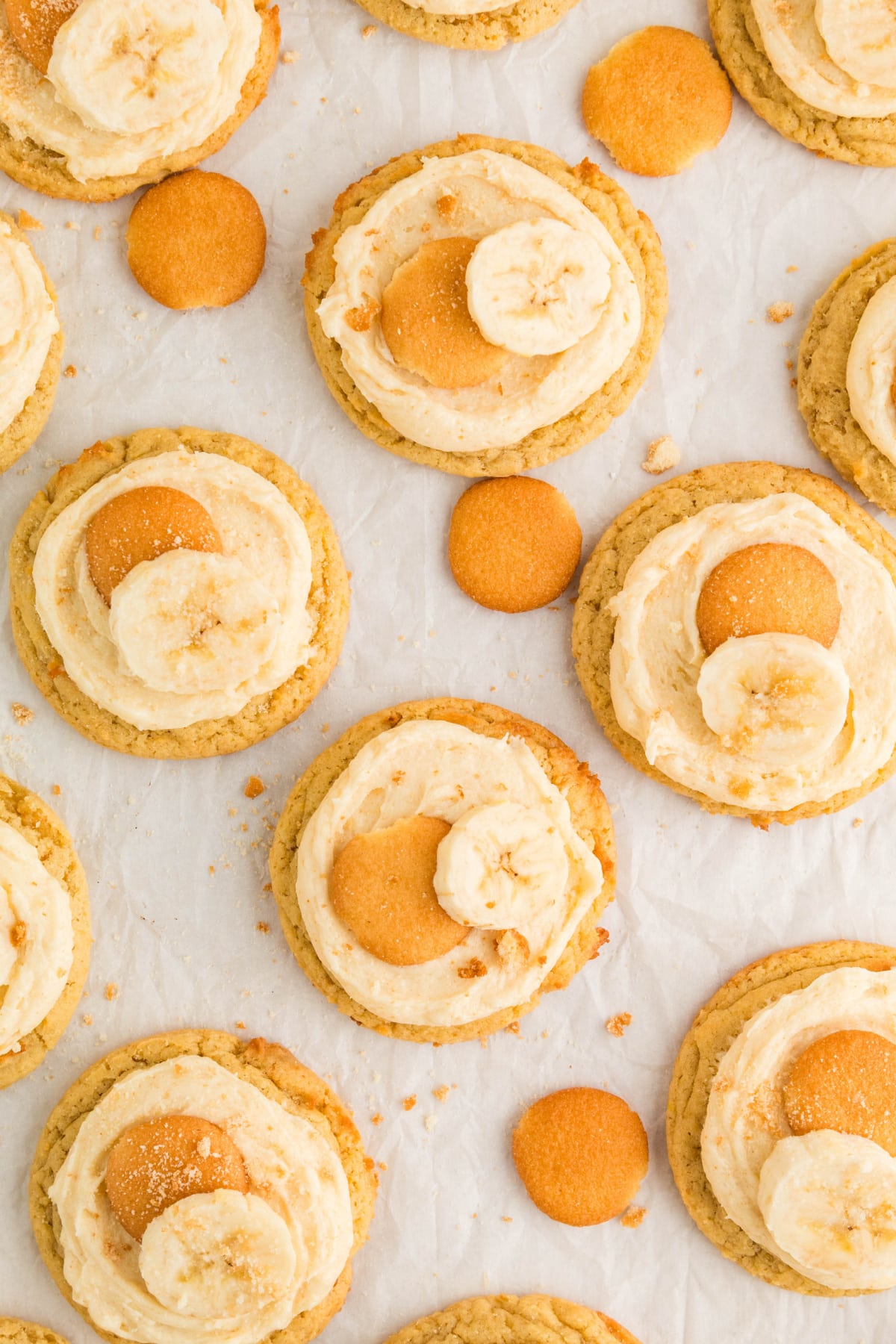 Overhead view of frosted banana pudding cookies topped with mini vanilla wafers and fresh banana slices.