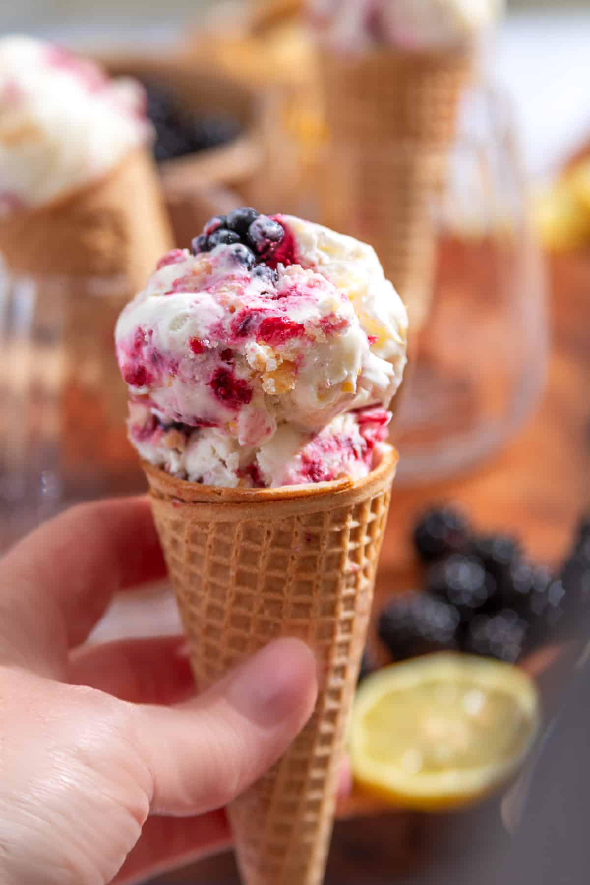 Blackberry Crumble à la Mode Ice Cream in a waffle cone with blackberry ribbons and buttery shortbread crumble.