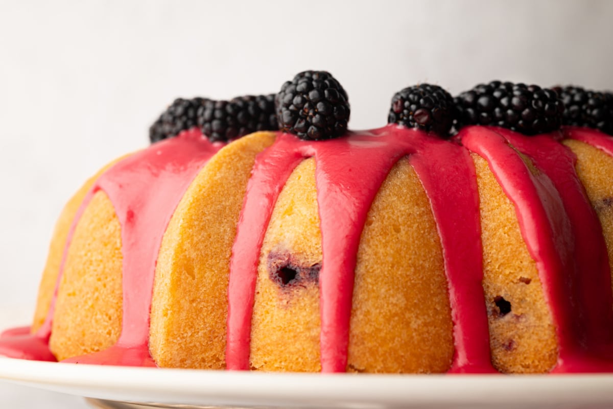 Fresh blackberry glaze dripping down the sides of a lemon Bundt cake topped with blackberries