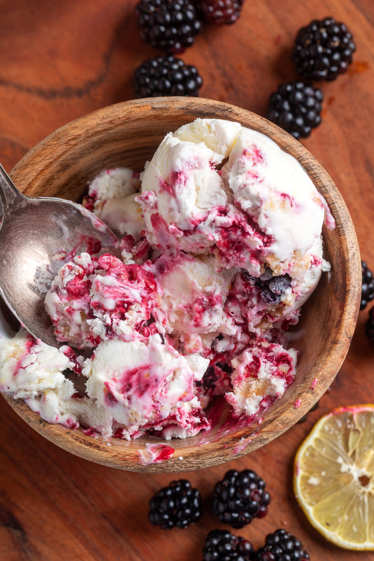 Homemade blackberry lemon ice cream with thick blackberry swirls and buttery shortbread crumble served in a wooden bowl.