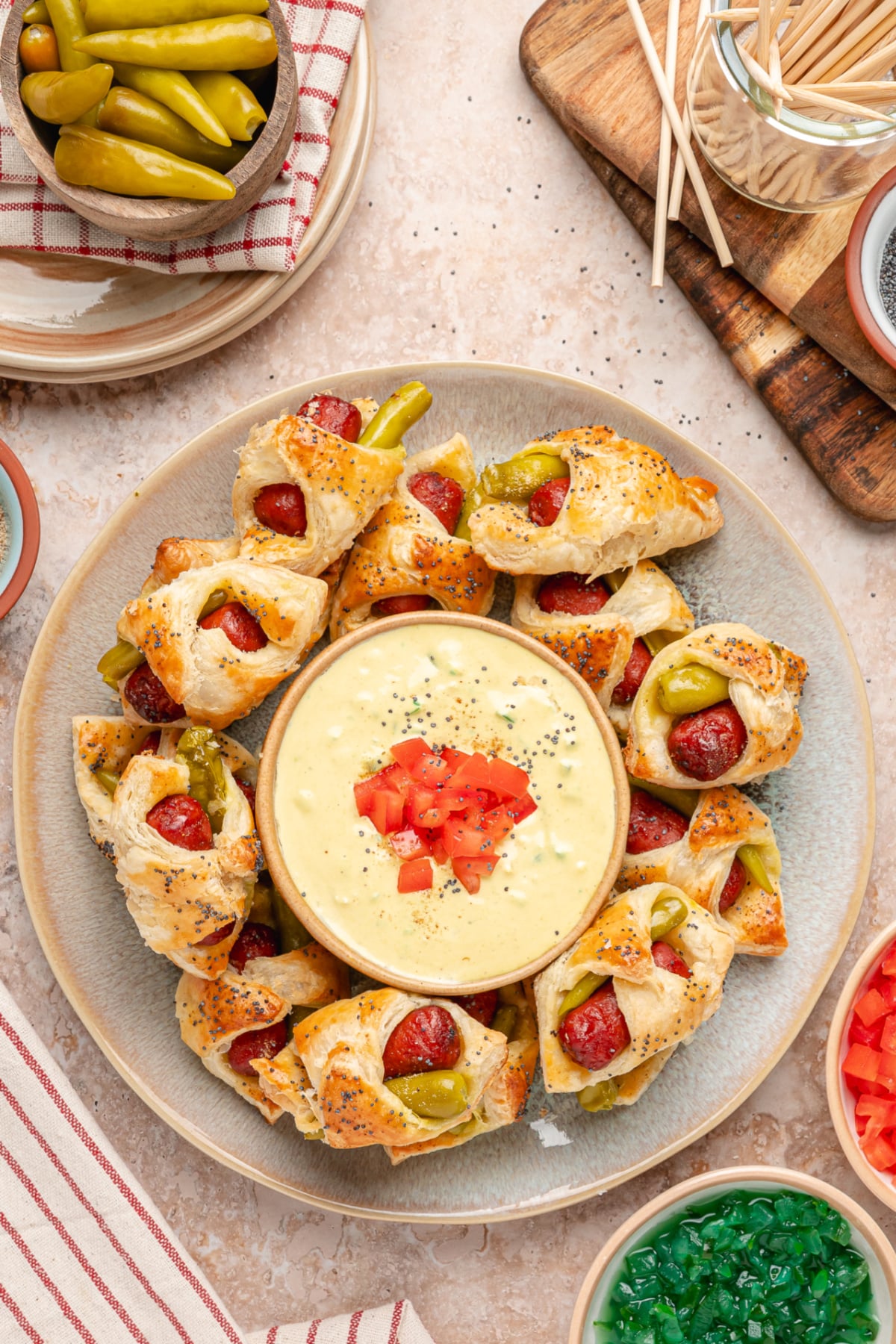 Chicago hot dog pigs in a blanket arranged around a creamy mustard relish dip topped with fresh tomato.