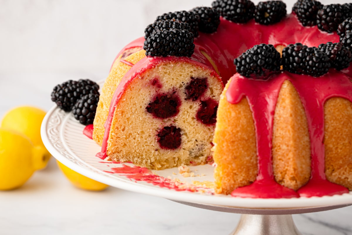 Slice removed from lemon blackberry Bundt cake showing whole blackberries baked throughout the cake