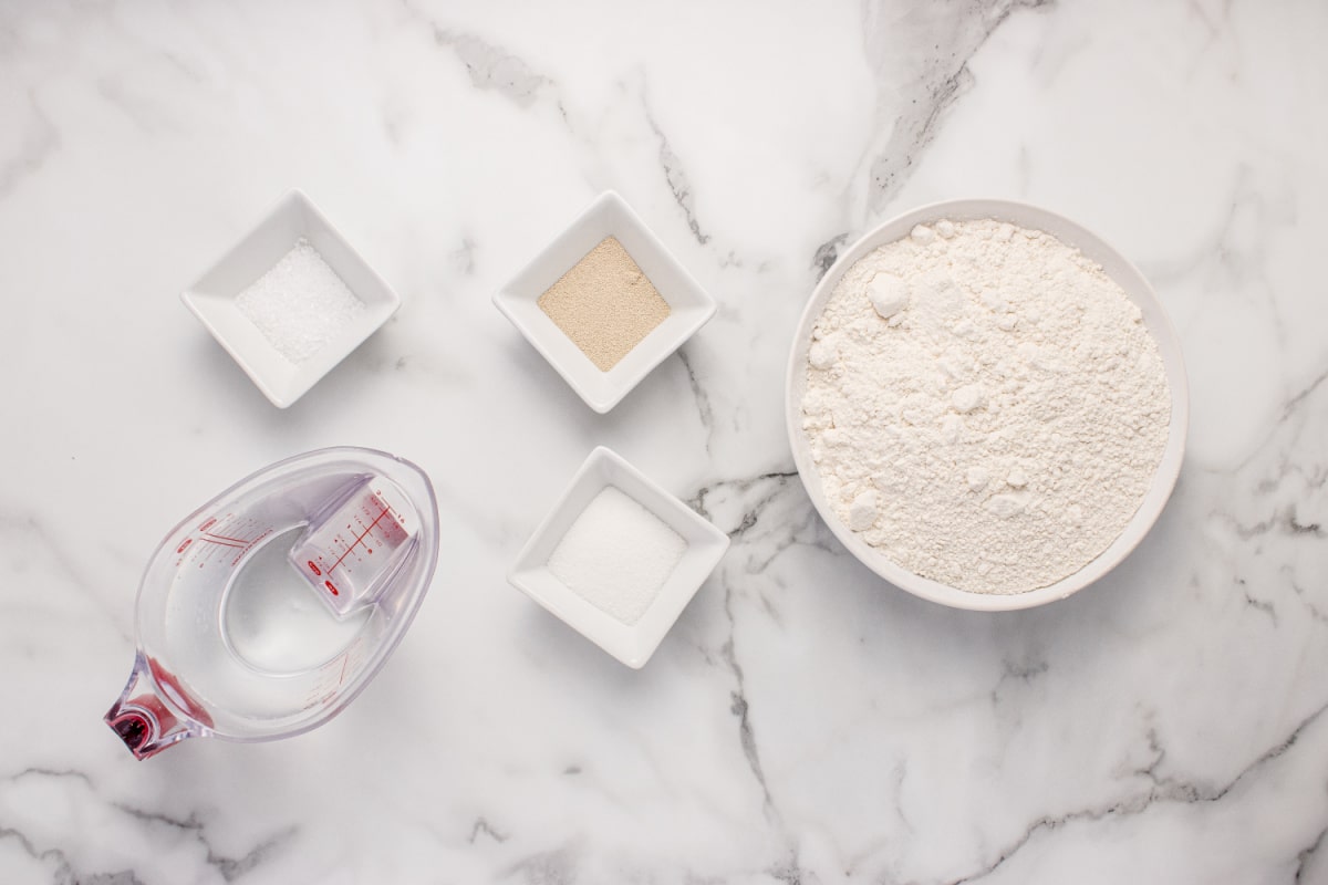 Ingredients for no-knead peasant bread including flour, yeast, sugar, salt, and water