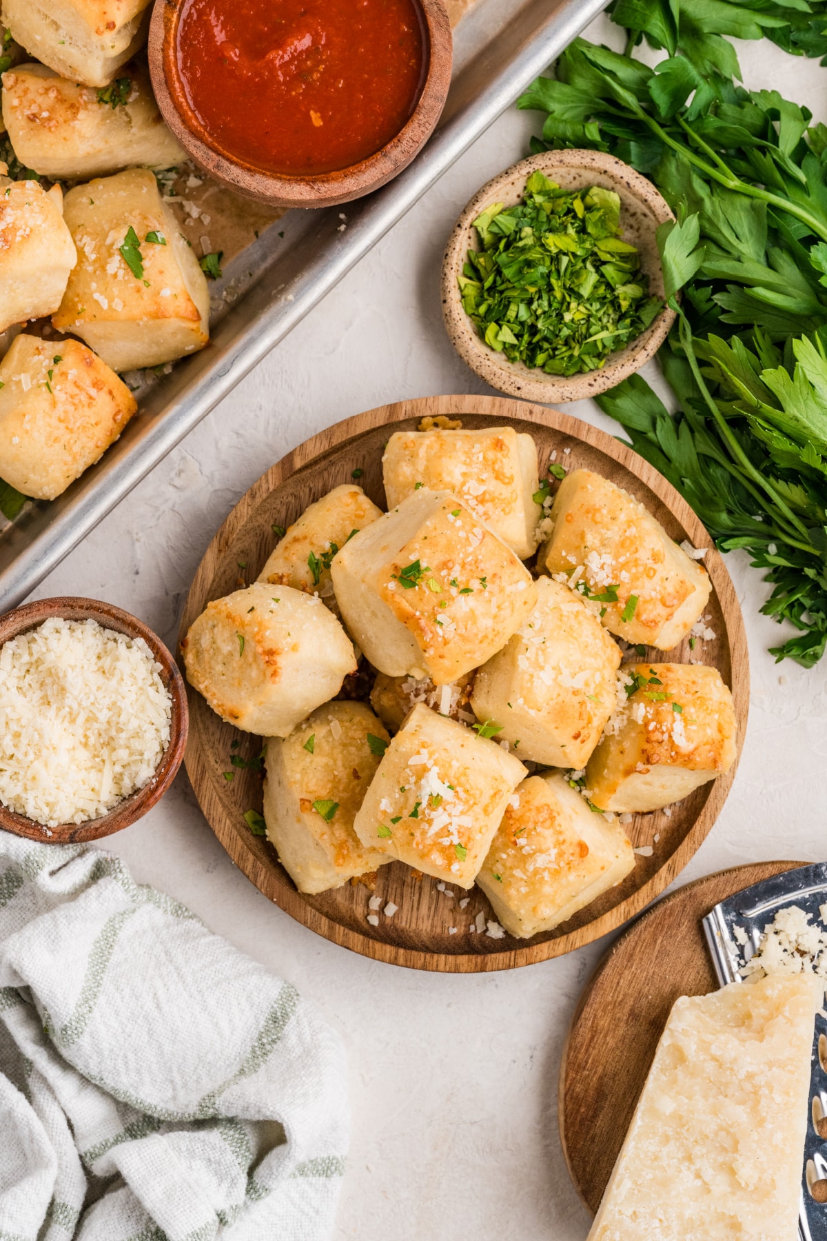 Parmesan bread bites on a serving platter with marinara sauce, Parmesan cheese, and fresh parsley