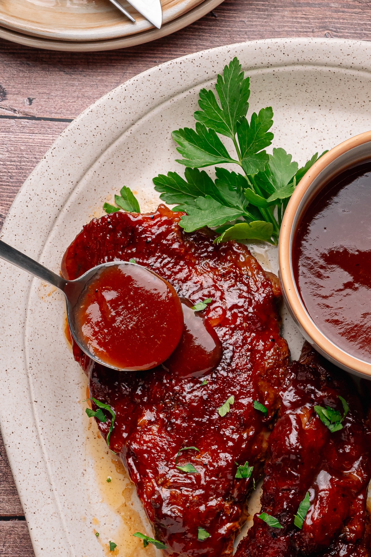 Peach bourbon barbecue sauce being spooned over glazed country style pork ribs