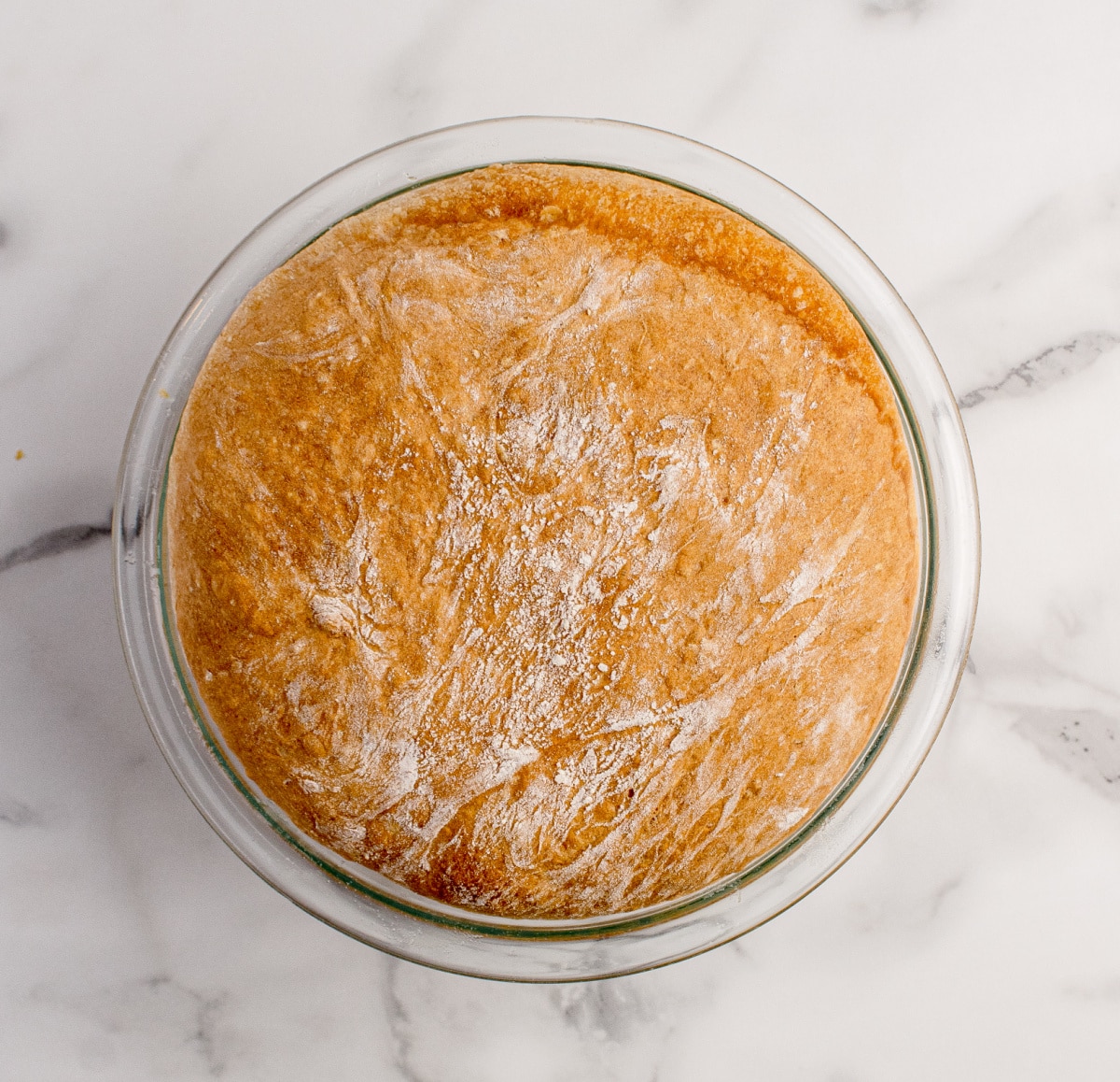 Overhead view of peasant bread baked in a glass bowl