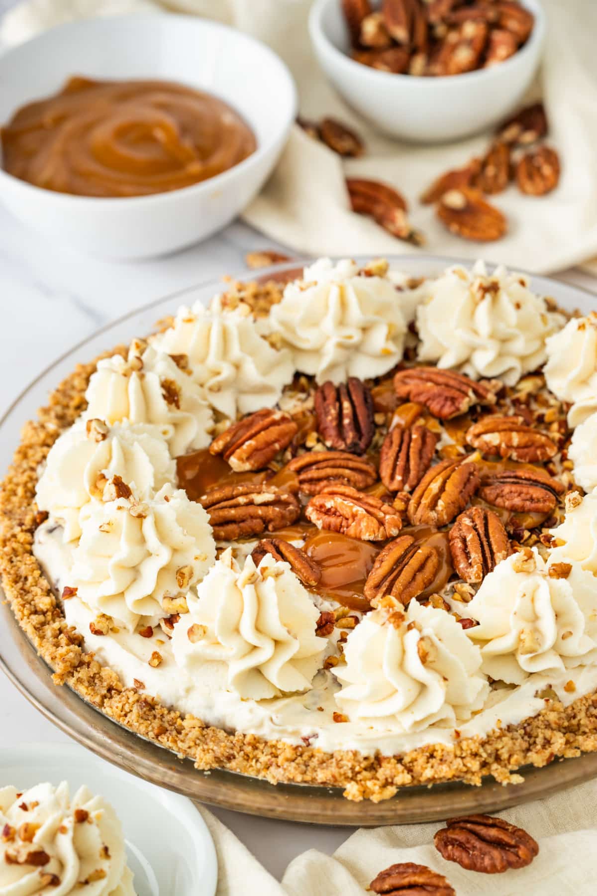 Pecan cream pie topped with toasted pecans, whipped cream, caramel drizzle, and a pecan crust