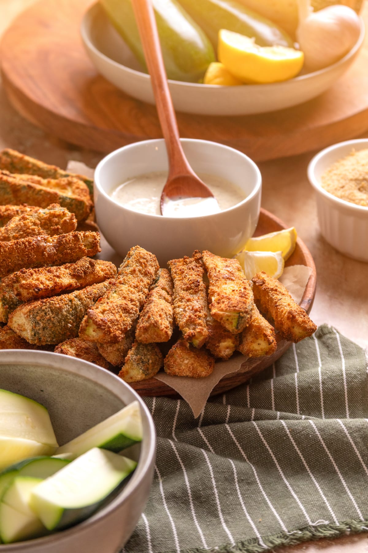 Serving board of crispy zucchini fries with homemade lemon garlic aioli and fresh zucchini.