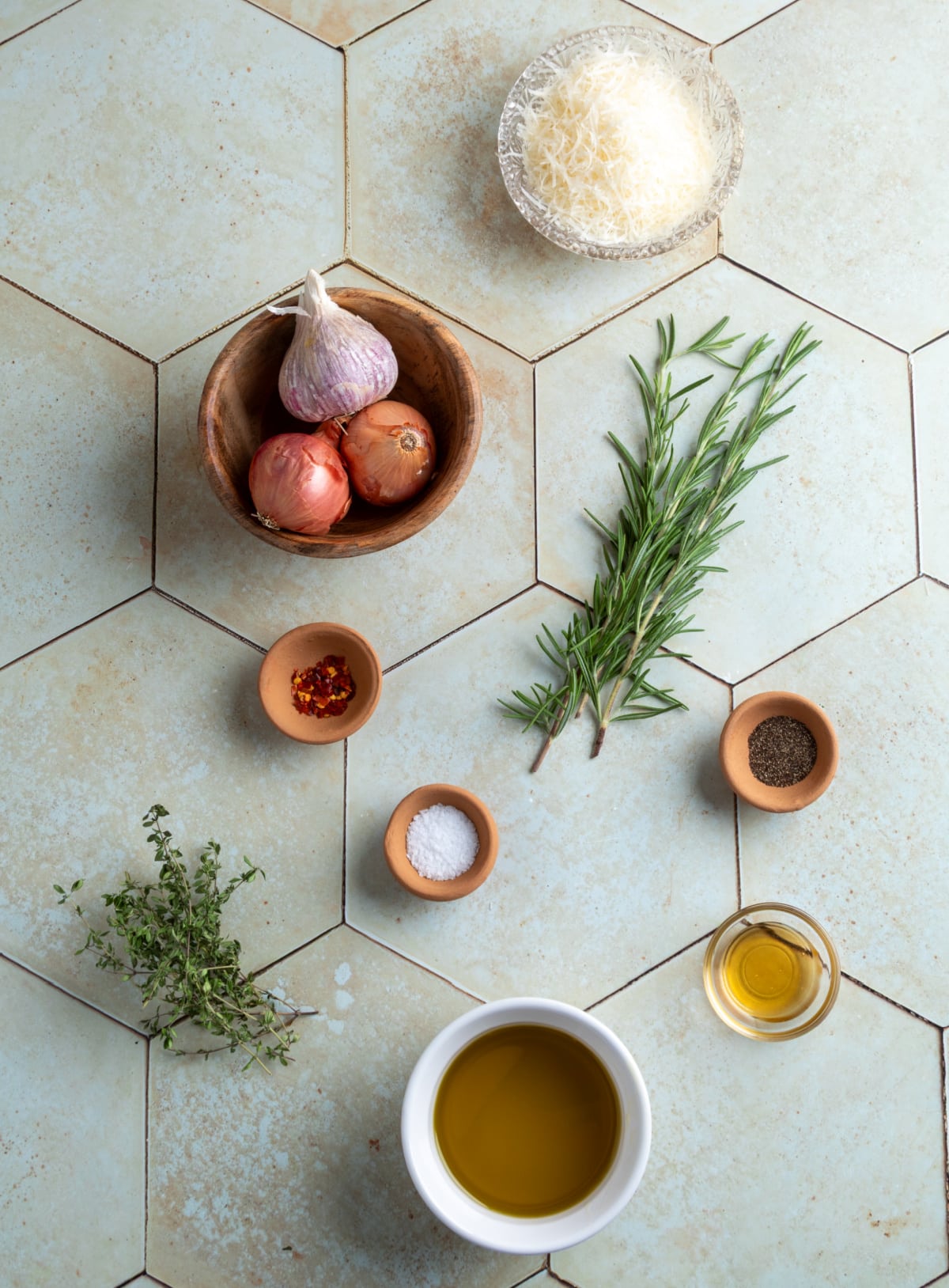 Ingredients for bread dipping oil including olive oil, shallots, garlic, rosemary, thyme, Parmesan, honey, salt, pepper, and red pepper flakes.
