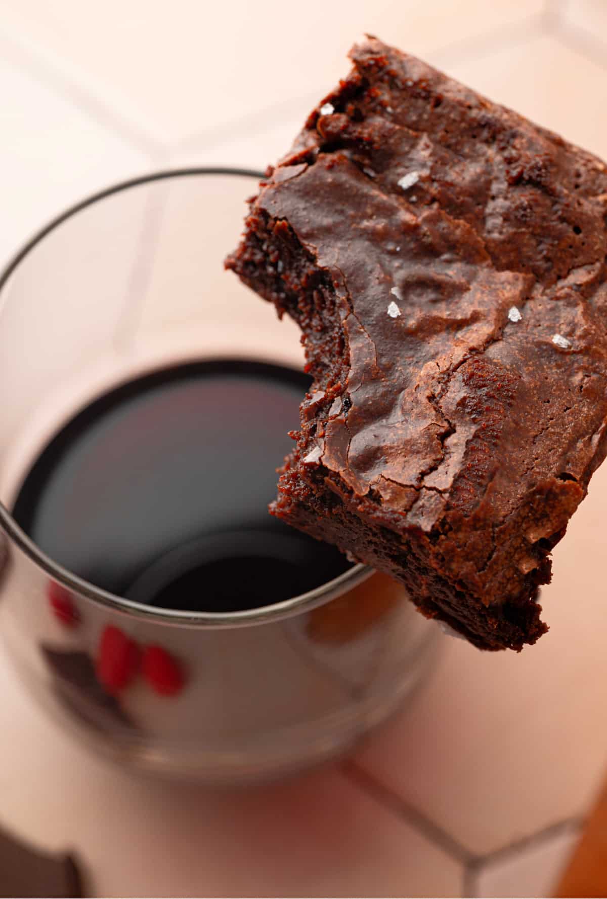 Cabernet Sauvignon brown butter brownie held over a glass of Cabernet Sauvignon.
