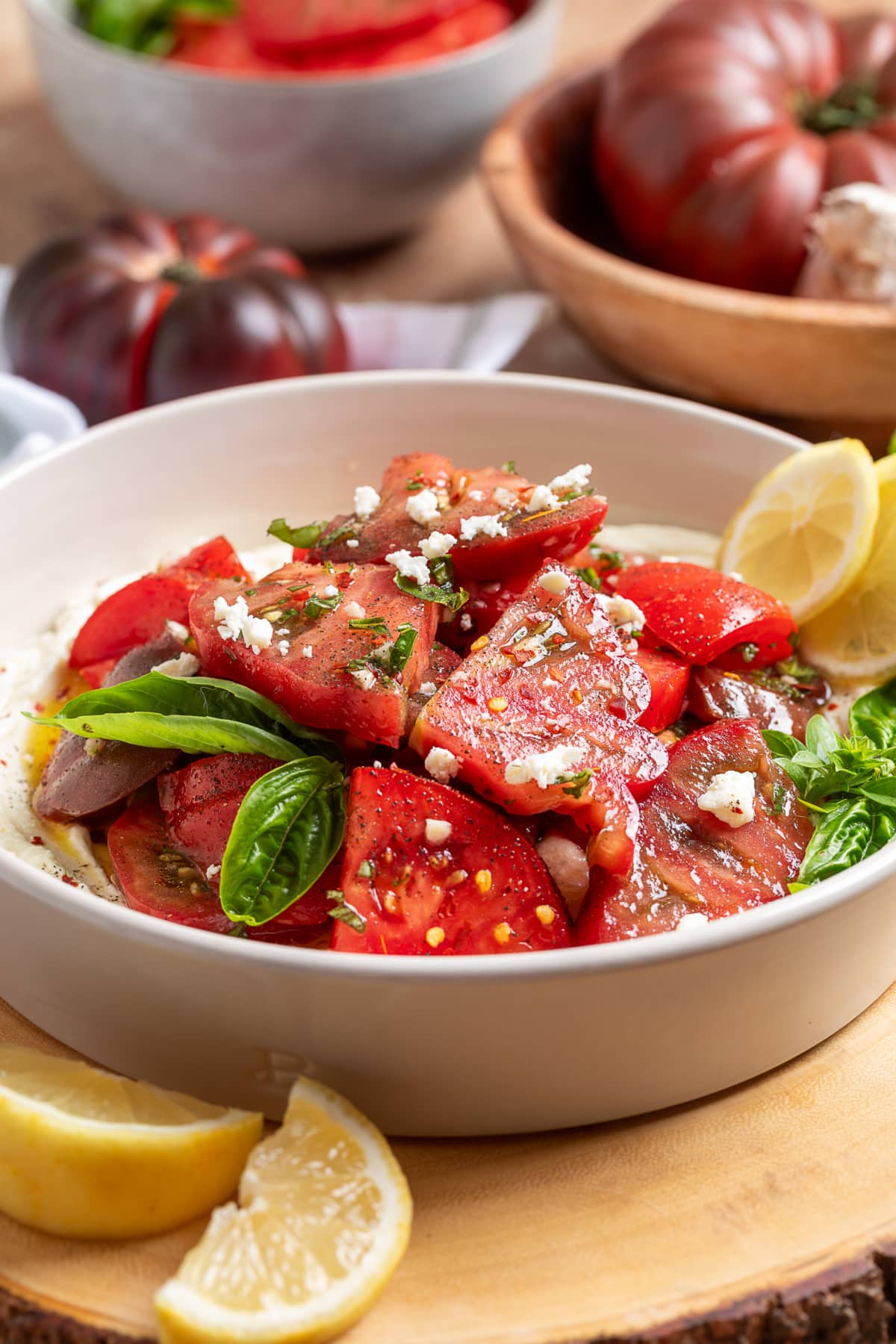 Vertical view of heirloom tomato salad with whipped ricotta feta, fresh basil, and lemon vinaigrette.