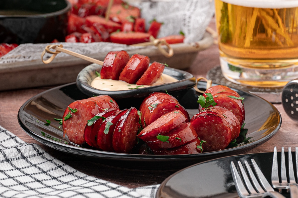 Honey garlic hasselback kielbasa bites on a plate with creamy honey mustard dipping sauce.