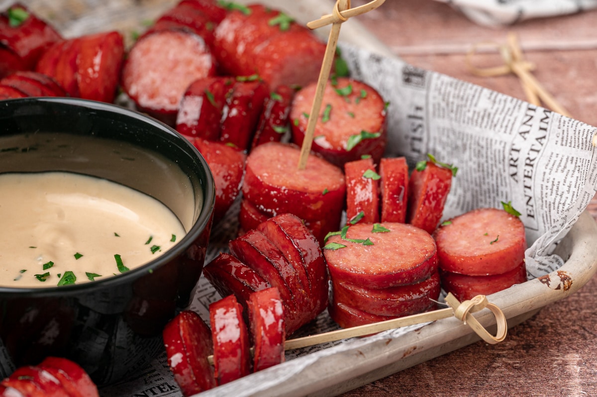 Honey garlic hasselback kielbasa bites served beside creamy honey mustard dipping sauce.