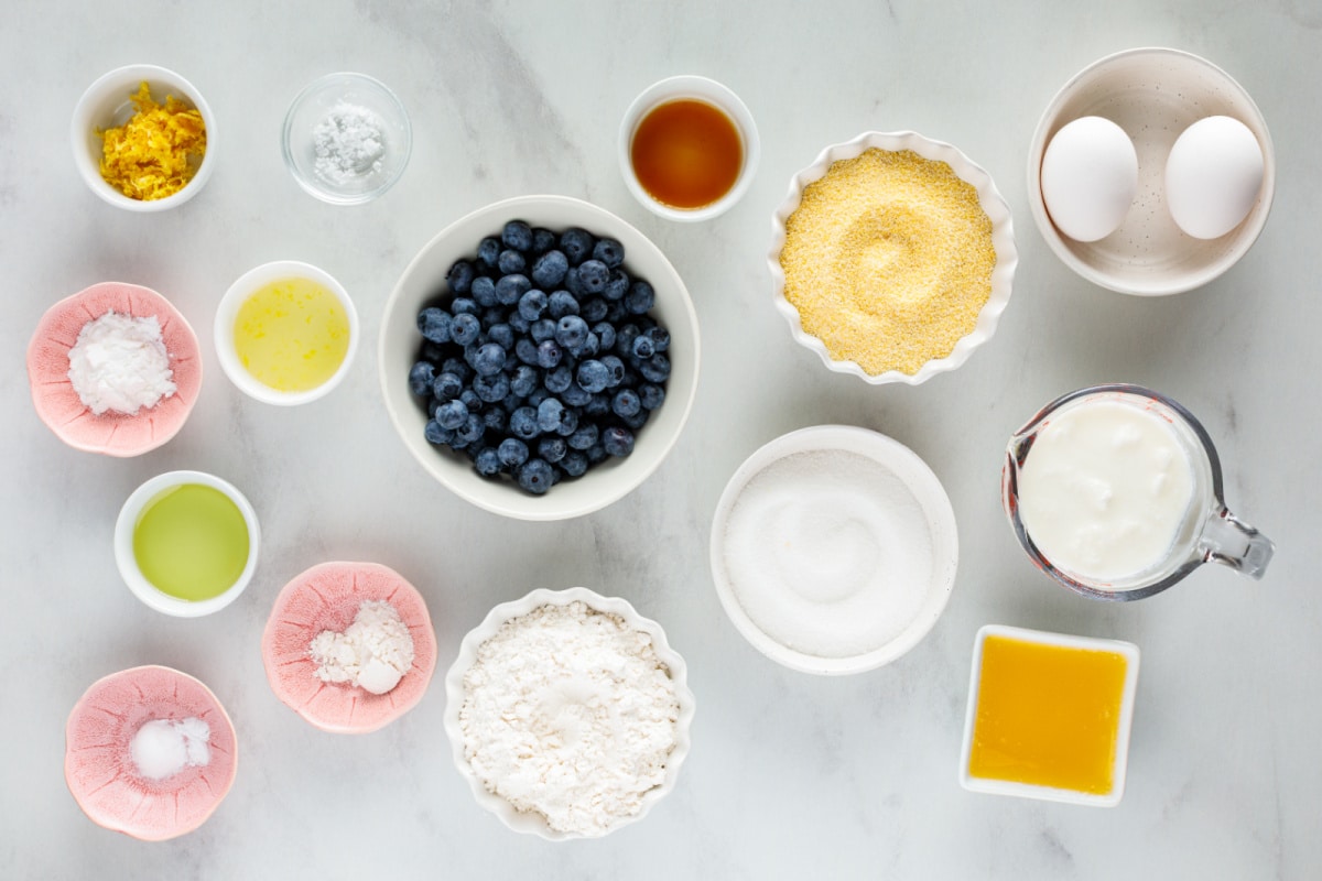 Ingredients for lemon blueberry cornbread including cornmeal, flour, buttermilk, fresh blueberries, lemons, eggs, butter, and lemon zest.