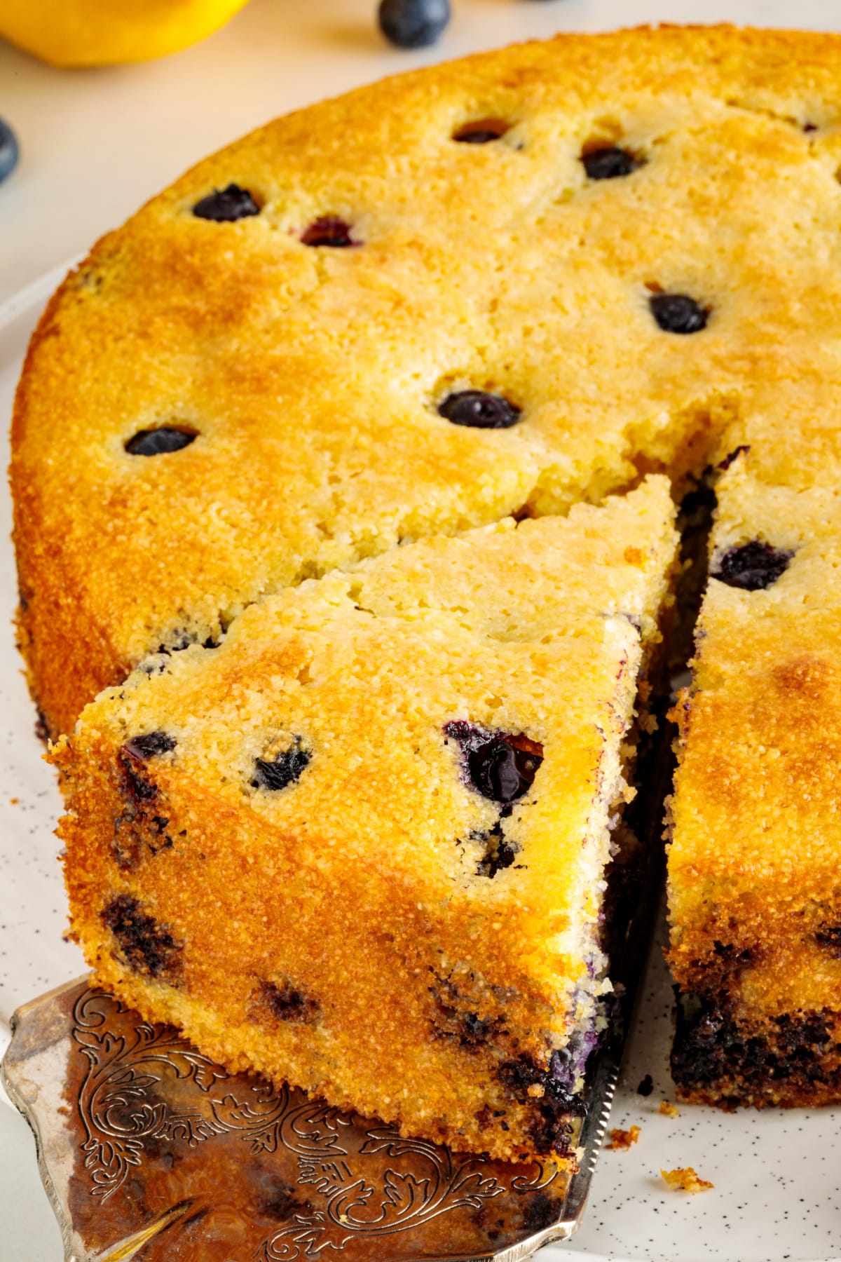Serving a slice of lemon blueberry cornbread, showing the golden crust and blueberries throughout the crumb.