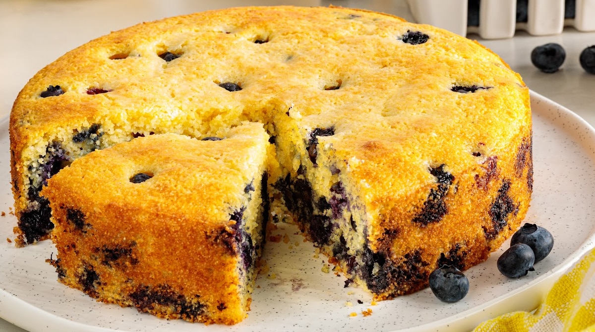 Lemon blueberry cornbread with one slice removed, showing the golden crust and blueberries throughout the tender crumb.
