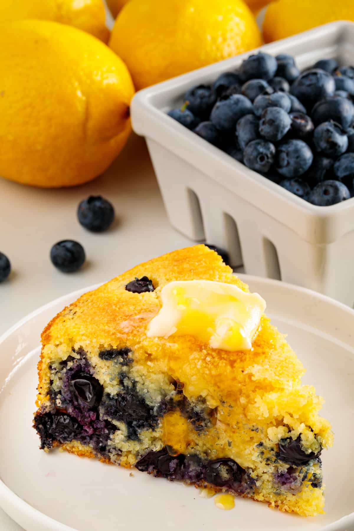 Lemon blueberry cornbread served warm with butter and honey, showing fresh blueberries throughout the tender crumb.