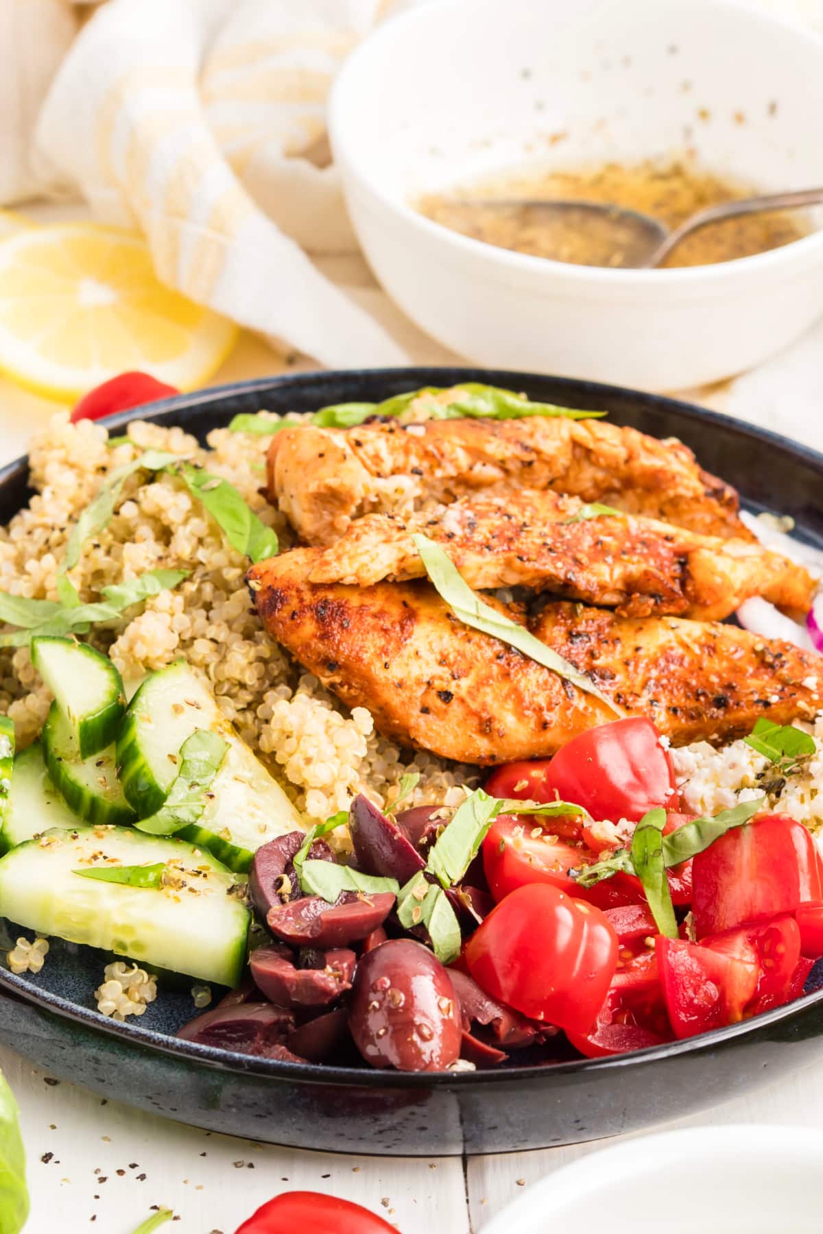 Mediterranean grilled chicken quinoa bowl with cucumber, cherry tomatoes, Kalamata olives, feta, fresh basil, and lemon vinaigrette.
