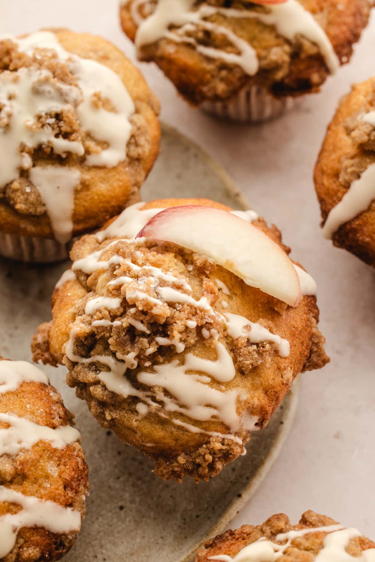 Peach coffee cake muffin with cinnamon streusel and vanilla glaze Peach coffee cake muffin topped with cinnamon streusel, vanilla glaze, and a fresh peach slice