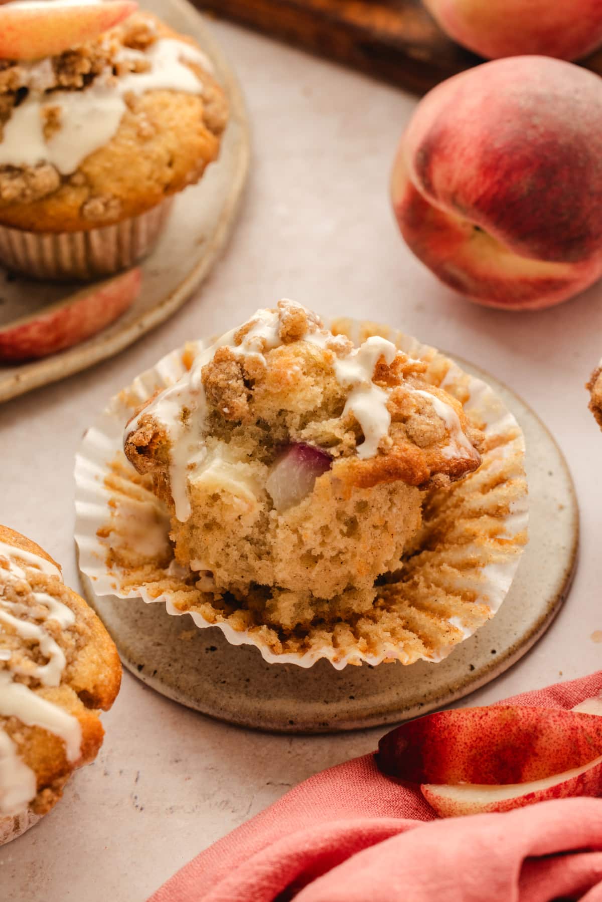 Peach coffee cake muffin filled with fresh peaches Peach coffee cake muffin with fresh peach pieces, cinnamon streusel, and vanilla glaze
