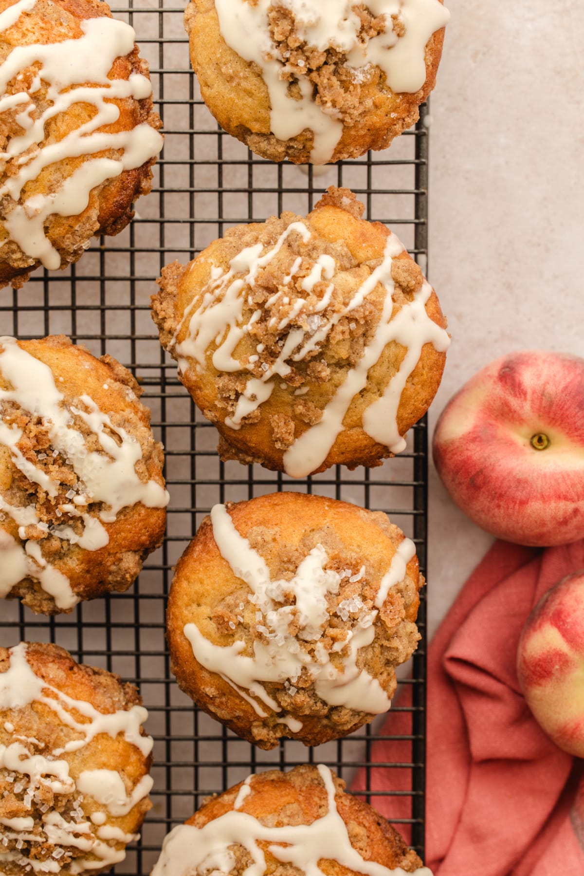 Peach coffee cake muffins cooling with cinnamon streusel and vanilla glaze Peach coffee cake muffins with cinnamon streusel, vanilla glaze, and fresh peaches