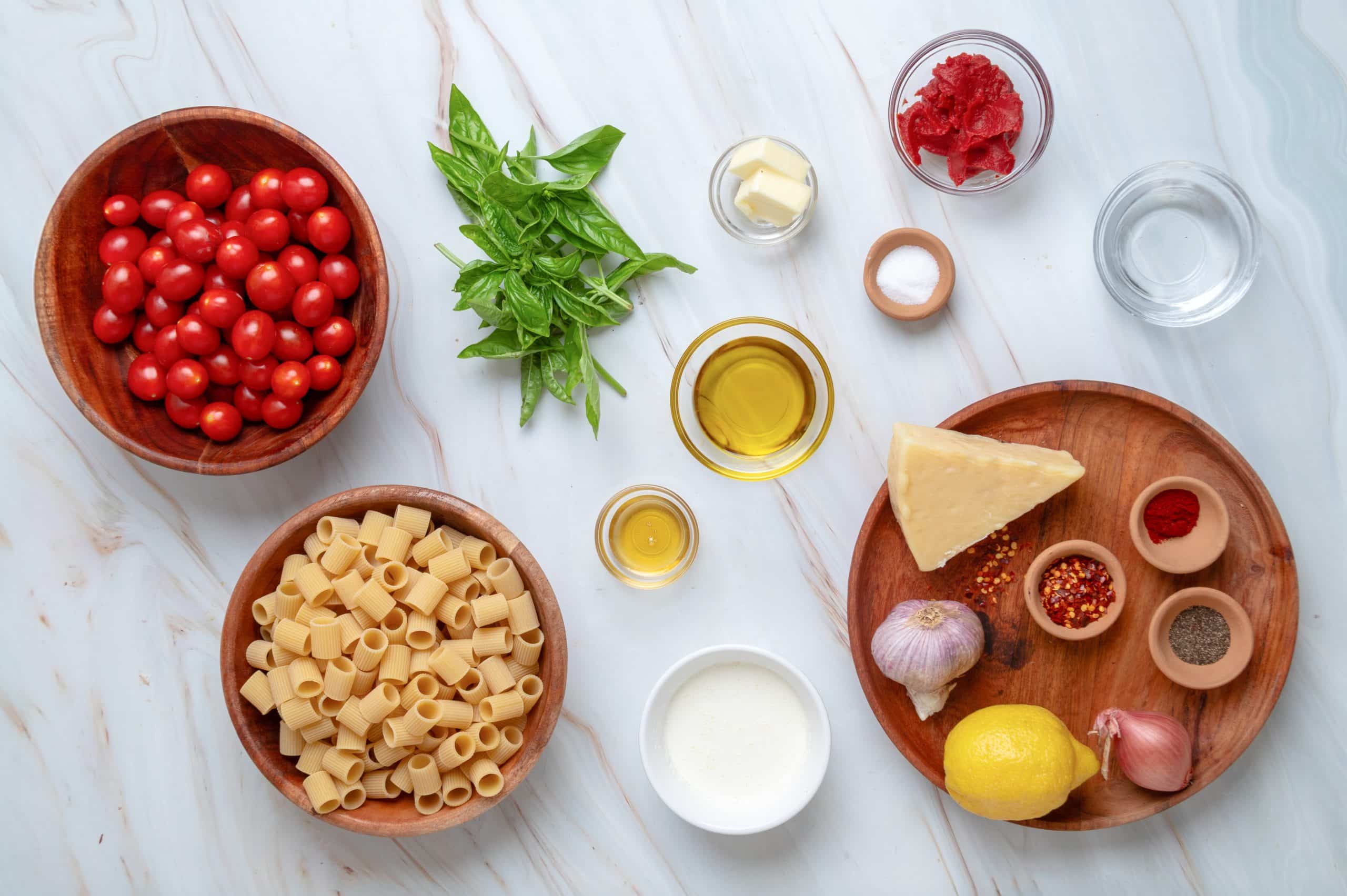Everything you need to make spicy roasted tomato vodka pasta. Ingredients for spicy roasted tomato vodka pasta, including mezzi rigatoni, grape tomatoes, tomato paste, Parmesan, heavy cream, shallot, garlic, basil, vodka, butter, olive oil, lemon, and seasonings.