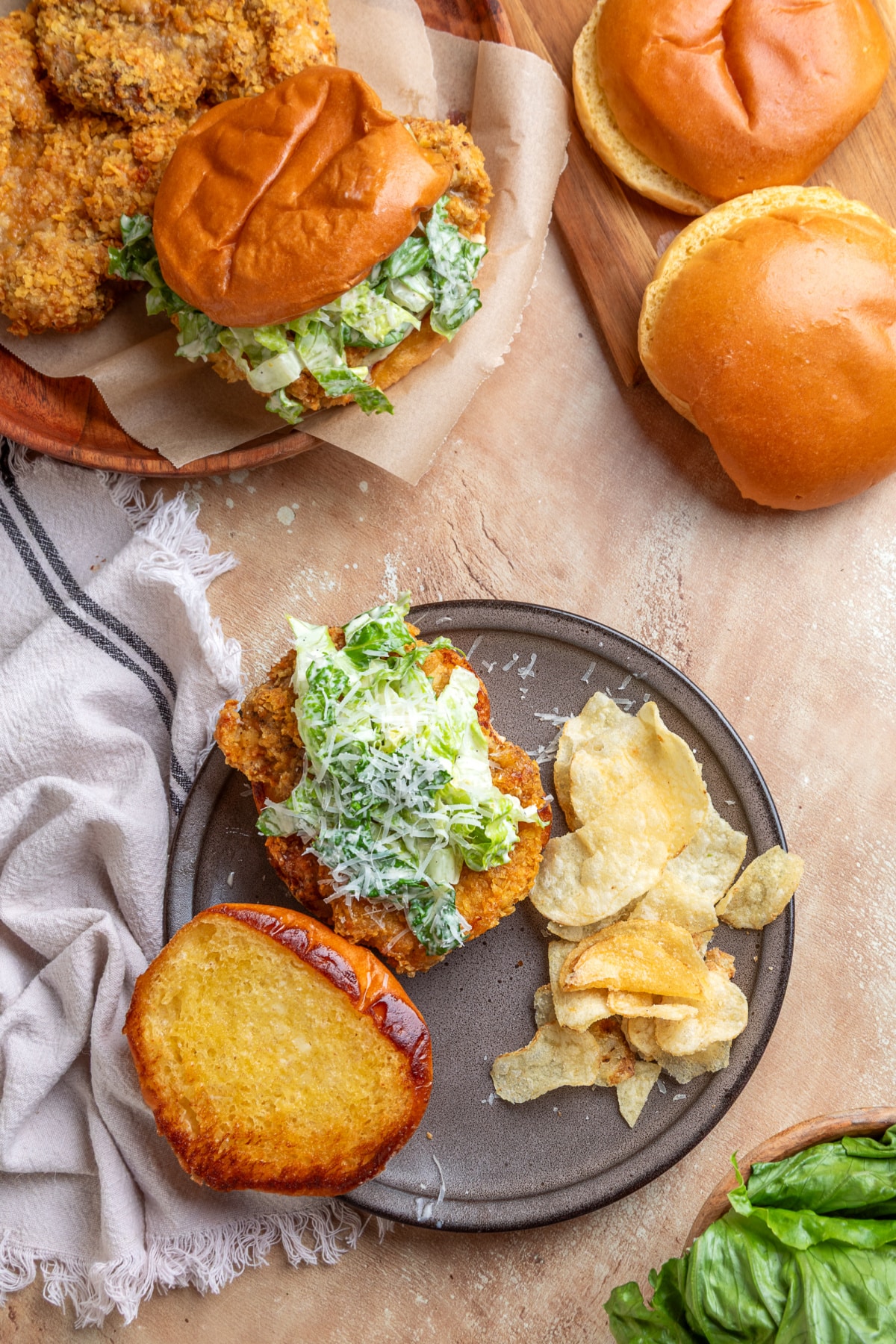 Overhead view of an air fryer chicken Caesar sandwich with crispy potato chip-crusted chicken, homemade Caesar salad, toasted brioche bun, and potato chips.