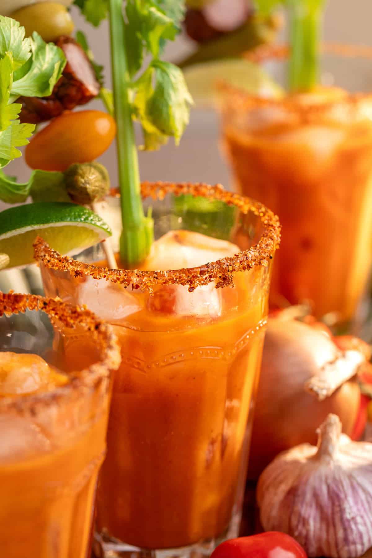 Bloody Mary cocktails made with smoked tomato mix over ice with Tajín rims, celery, lime and savory garnishes