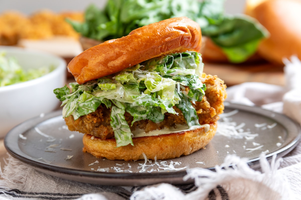 Chicken Caesar salad sandwich with crispy potato chip-crusted chicken cooked in the air fryer, homemade Caesar salad, and Parmesan cheese on a toasted bun.