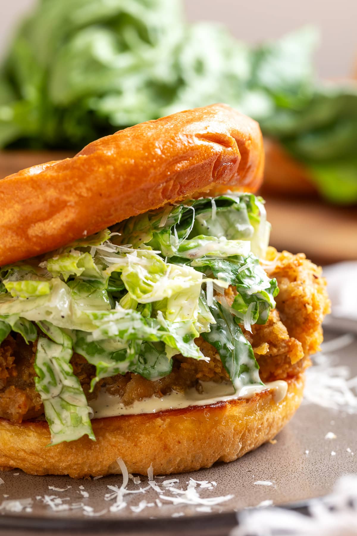 Chicken Caesar salad sandwich with crispy potato chip-crusted chicken, homemade Caesar salad, Parmesan cheese, and a toasted brioche bun.