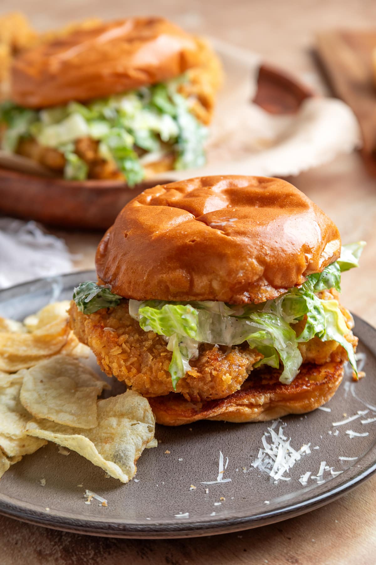 Chicken Caesar sandwich with crispy potato chip-crusted chicken, homemade Caesar salad, and a toasted brioche bun served with potato chips.