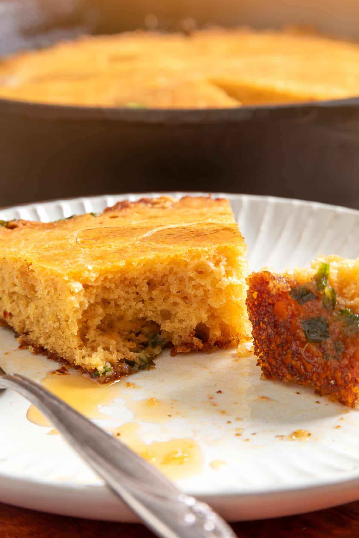 Chipotle hot honey skillet cornbread slice showing the tender interior and jalapeños baked along the bottom